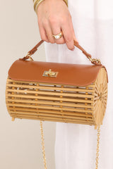 Front view of this bamboo handbag that features a top handle, a single flap design, a twist lock closure, and a removable chain strap. 