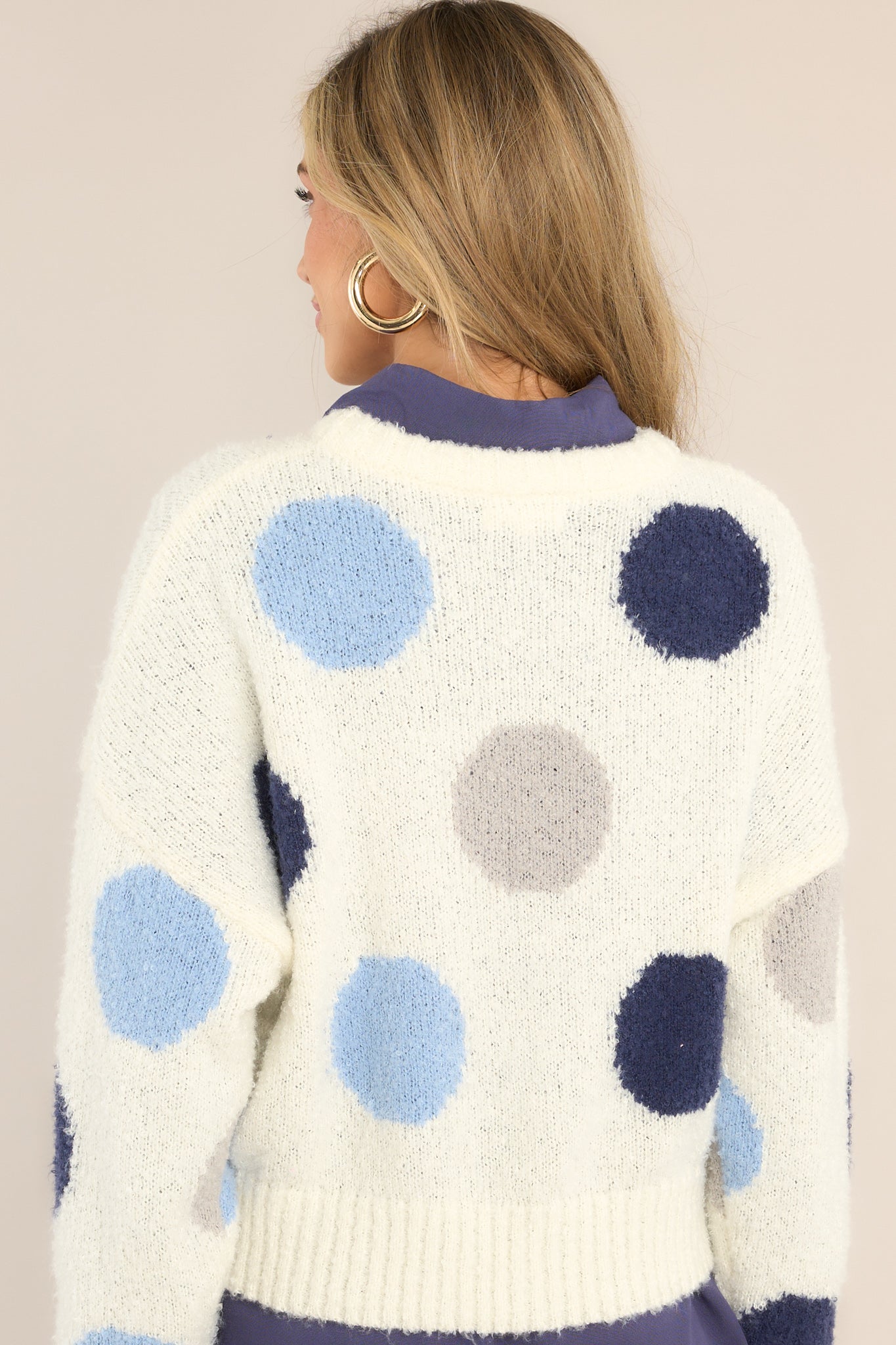 Back view of this sweater that features a crew neckline, dropped shoulders, a blue polka dot design, ribbed cuffed sleeves and a ribbed hemline.