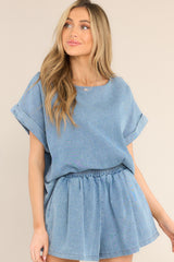 This chambray colored top features a crew neckline, a denim-like material, and cuffed short sleeves.