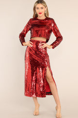 This red sequin top features an all over sequin flip design, long sleeves, and a cropped hemline.