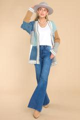 This blue color-blocked cardigan features a v-neckline, functional buttons down the front, stripe detailing along the hem and cuffs, cable knit detailing, and a soft, knit material throughout.