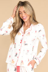 This ivory top features a collared neckline, functional buttons down the front, and a festive print.
