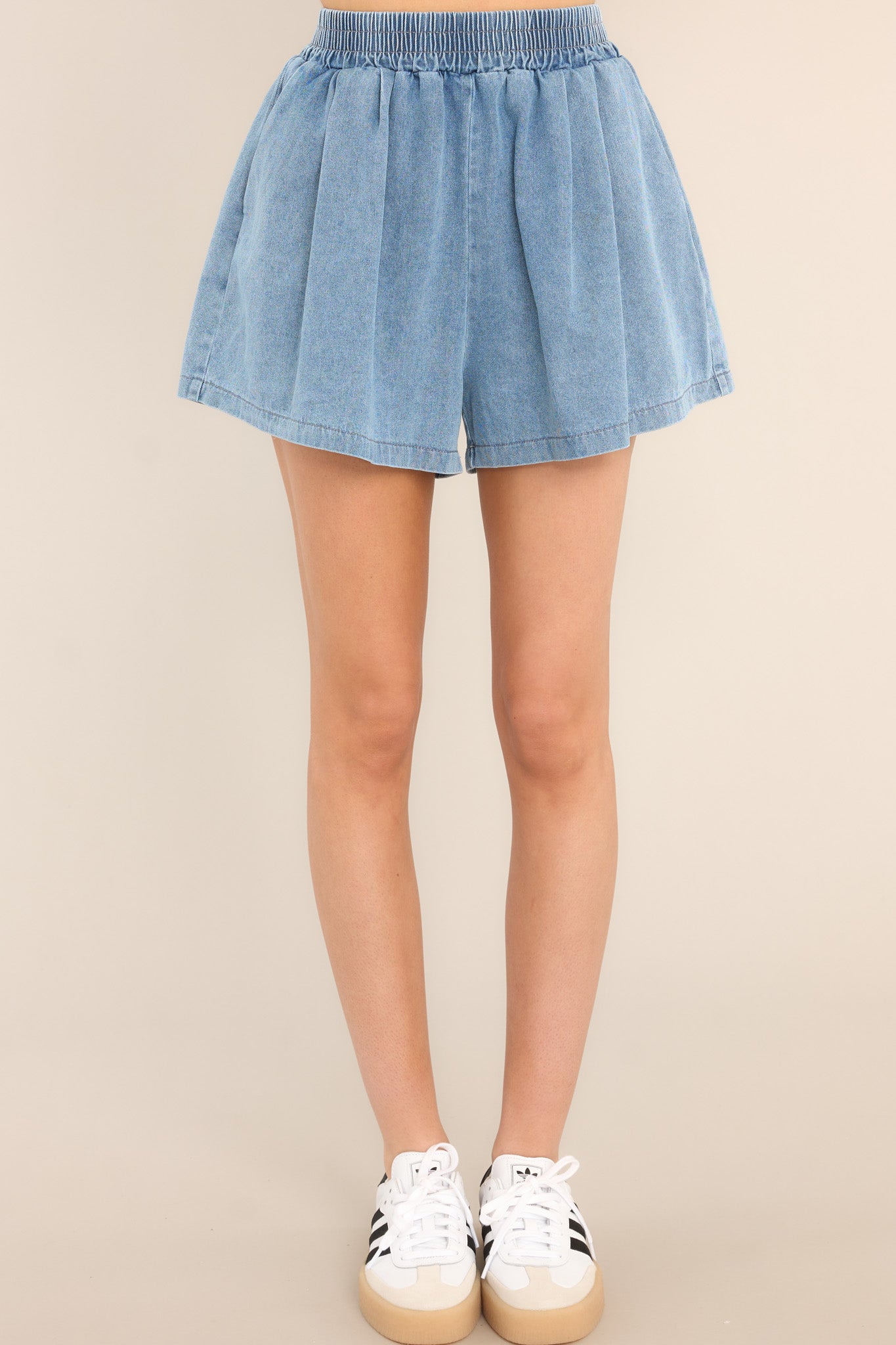 Front view of these shorts that feature an elastic waistband, functional hip pockets, and a high low hemline. 