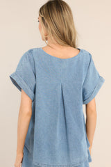 Back view of  this top that features a crew neckline, a denim-like material, and cuffed short sleeves.