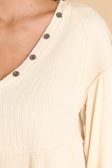 Close up view of this top that features a v-neckline with button detailing, and a waffle knit material.