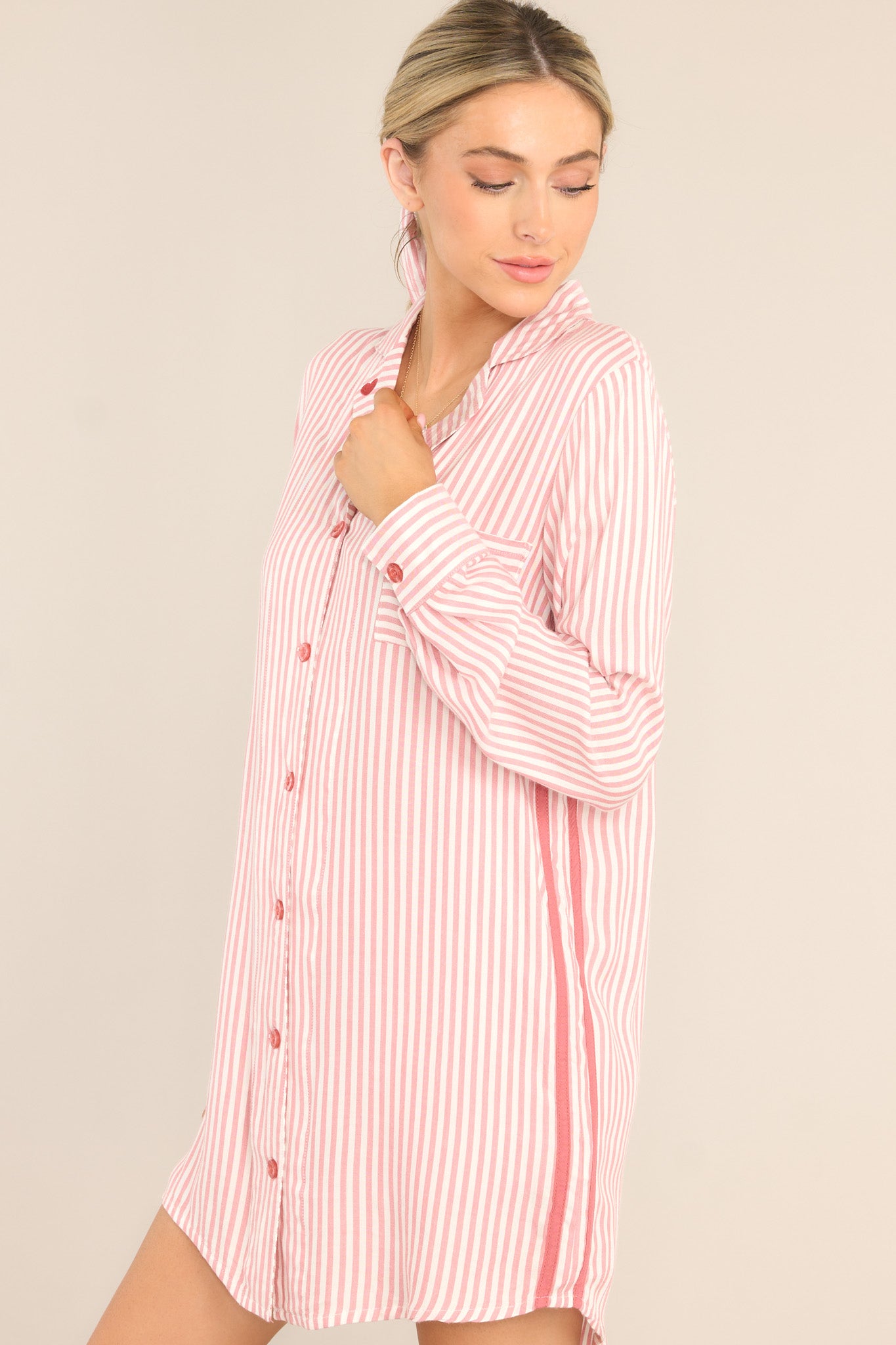 Side view of this nightshirt that features a notched lapel collared neckline with embroidered heart detailing, a chest pocket, a full button front, a contrasting side seam, and buttoned cuffed long sleeves.