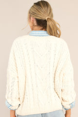 Back view of this sweater that features a ribbed v-neckline, long sleeves with ribbed cuffs, a bottom hem that tapers in, and a chunky knit design throughout.