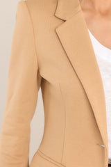 Close up view of this blazer that features a notch lapel collar, shoulder pads, a functional button, faux pockets, and faux buttons on the sleeves.