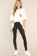 Full body view of this top that features pink rhinestone hearts throughout, short sleeves, crew neckline, and oversized fit.