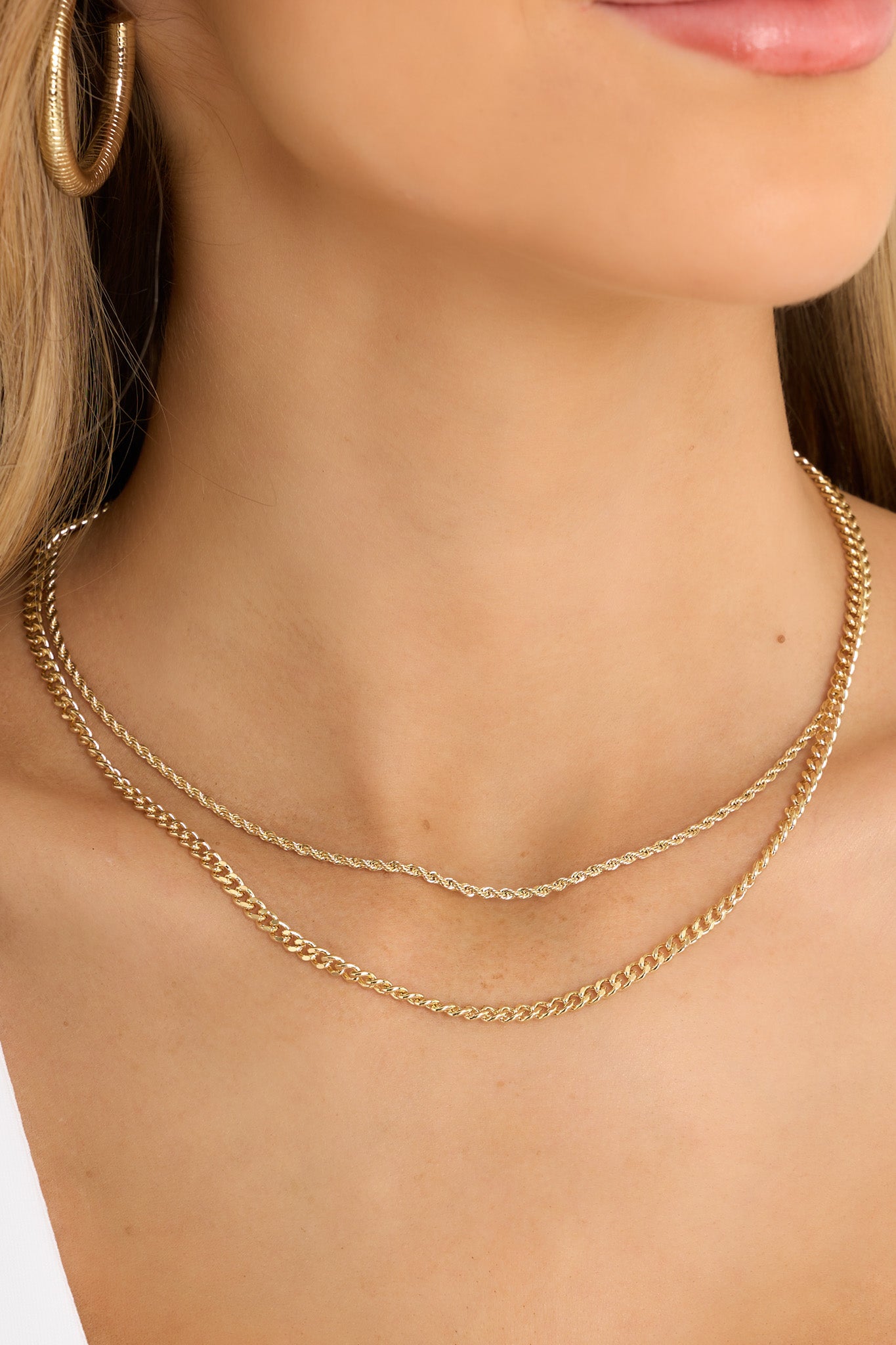This gold necklace features gold hardware, a rope chain, a curb chain, and a lobster claw closure. 