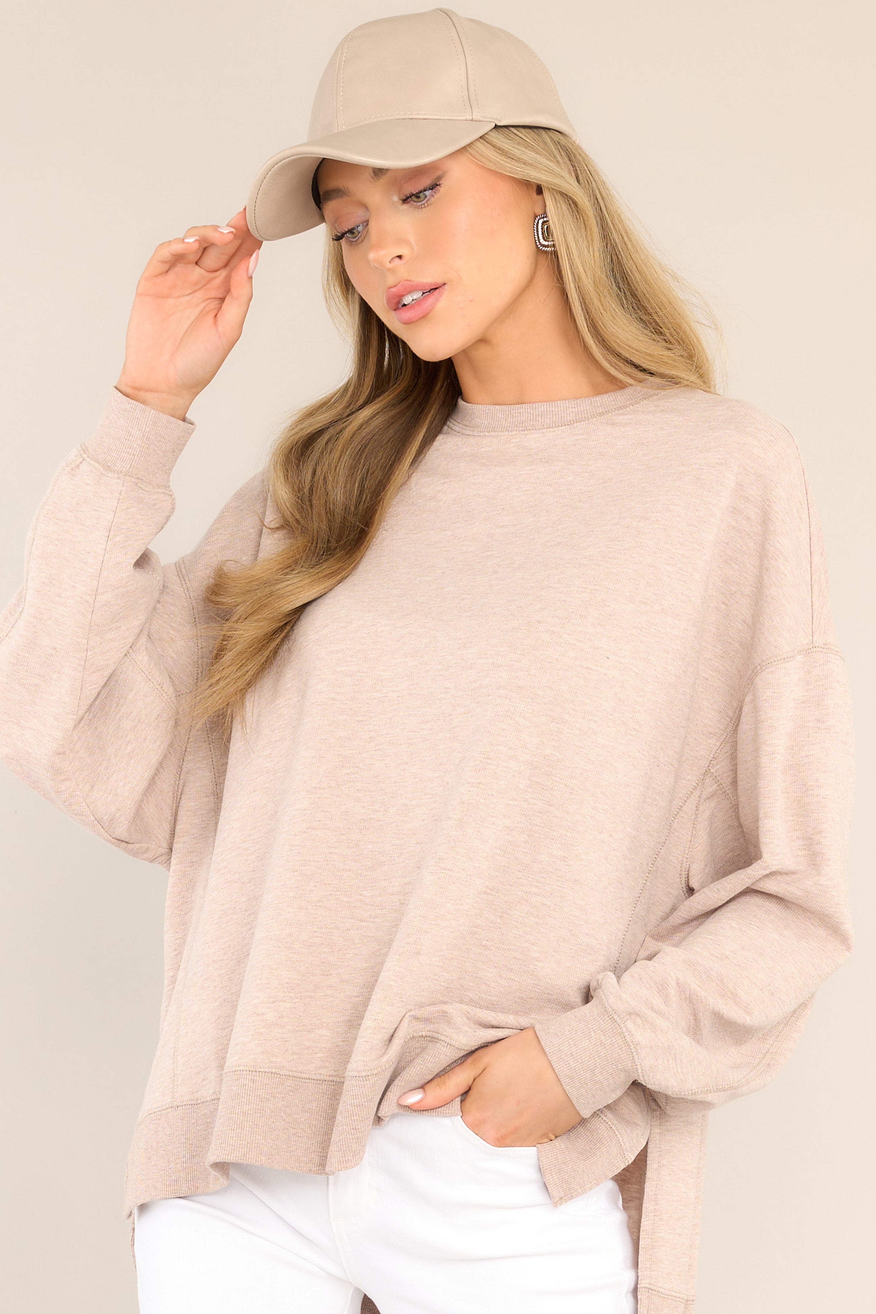 This light brown top features a crew neckline, dropped shoulders, ribbed cuffed sleeves, and a high-low split hemline.