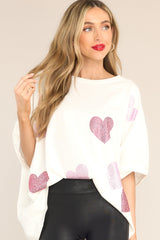 Front view of this top that features pink rhinestone hearts throughout, short sleeves, crew neckline, and oversized fit.