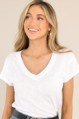 Tucked in view of model wearing white v-neck tee that features short sleeves.