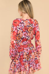 Back view of this dress that features a v-neckline with a self-tie string, long sleeves with elastic cuffs, an elastic waistband, and a flowy skirt.