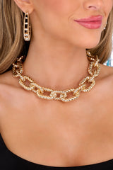 Model shown wearing necklace that features large gold chain link pattern, and a lobster closure.