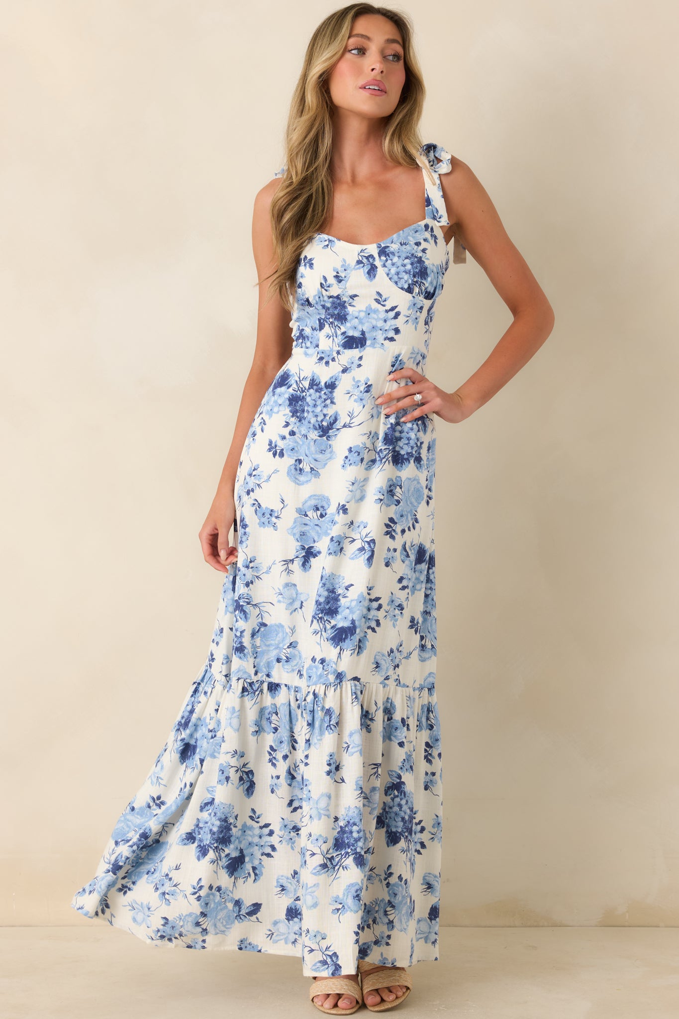 Blue floral midi dress with ivory backdrop, tie straps, and softly tiered silhouette.

