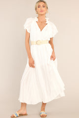 Full body view of this dress that features a v-neckline with ruffle detailing and a self-tie feature, a self-tie waist belt, and a flowy skirt.