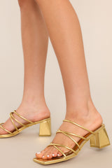 These gold heels feature a rounded toe, a slip-on design crisscross straps across the top of the foot, and a short, thick heel.