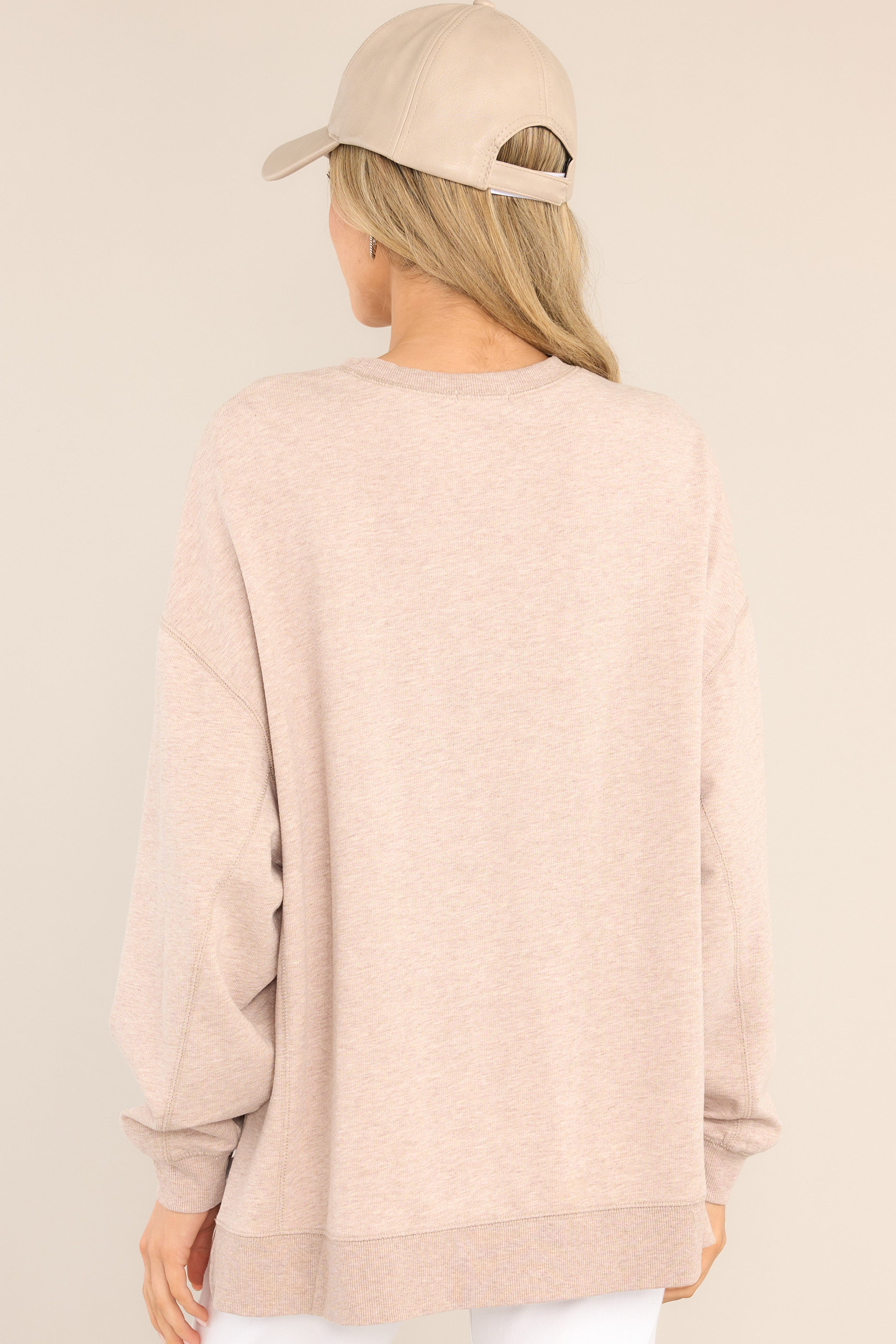 Back view of this top that features a crew neckline, dropped shoulders, ribbed cuffed sleeves, and a high-low split hemline.