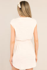 Back view of this dress that features a crew neckline, smocking in the waist, a textured material, and a scooped hemline.