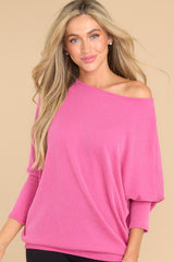 Front view of this top that features a round neckline, long dolman sleeves, and a slight high low hem line.