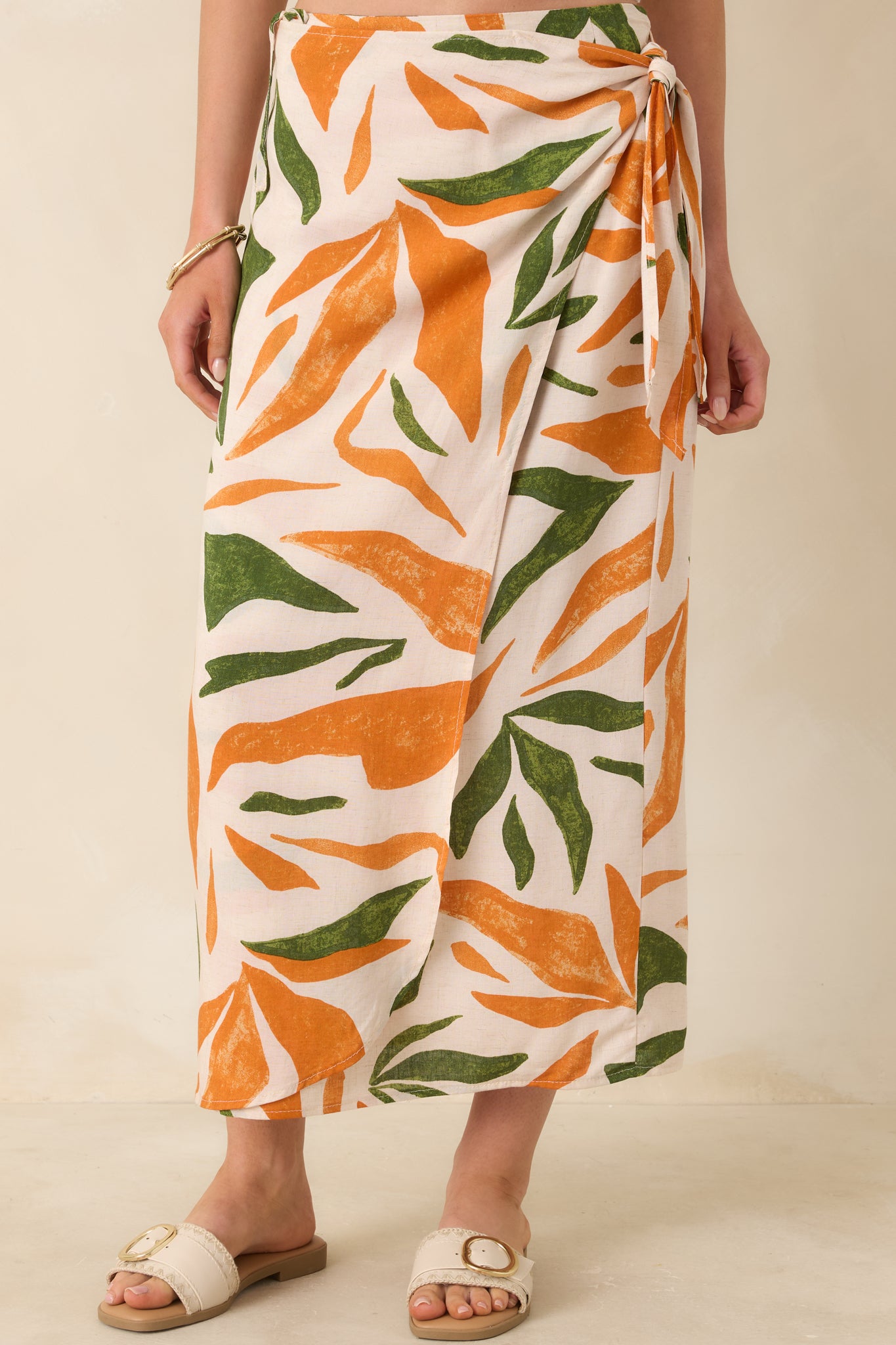Front view of this tropical print midi skirt that features a high waisted design, an elastic waist insert, self-tie wrap features, an orange & green tropical print, and a lightweight fabric.