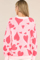 Back view of this sweater that features a round ribbed neckline, long sleeves, tinsel-like hearts, and a fun pattern throughout.