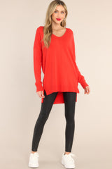This all red sweater features a v-neckline, a high low hem, slits on the sides, and ribbed detailing on the cuffs and hem.