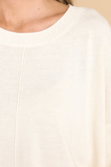 Close up view of this sweater that features a crew neckline, a high low hemline, and cuffed sleeves.