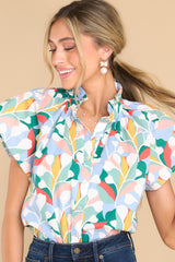 This blue cotton top features a ruffled faux collar neckline, flutter sleeves, and functional buttons down the front.