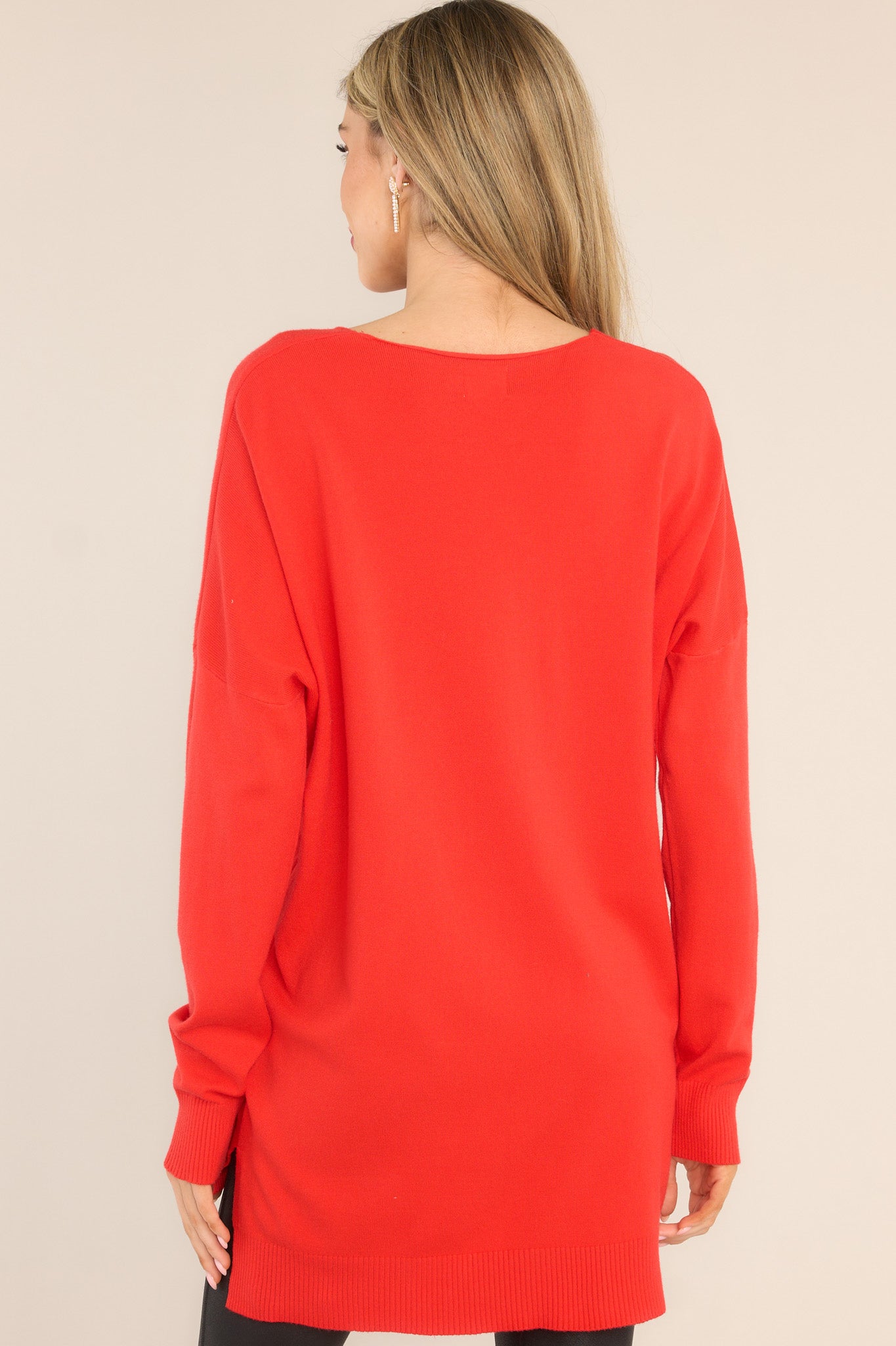 Back view of this sweater that features a v-neckline, center seam down the front, a high low hem, slits on the sides, and ribbed detailing on the cuffs and hem.