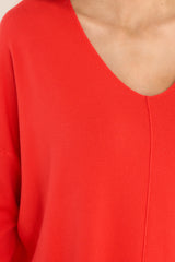Close up view of this sweater that features a v-neckline, center seam down the front, a high low hem, slits on the sides, and ribbed detailing on the cuffs and hem.