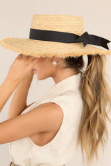 This natural straw hat features a frayed brim that measures 12cm/4.50in wide, a soft boater crown, and black ribbon trim. 