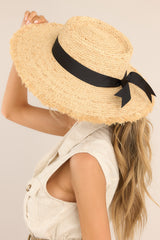 Side view of this straw hat that features a frayed brim that measures 12cm/4.50in wide, a soft boater crown, and black ribbon trim.