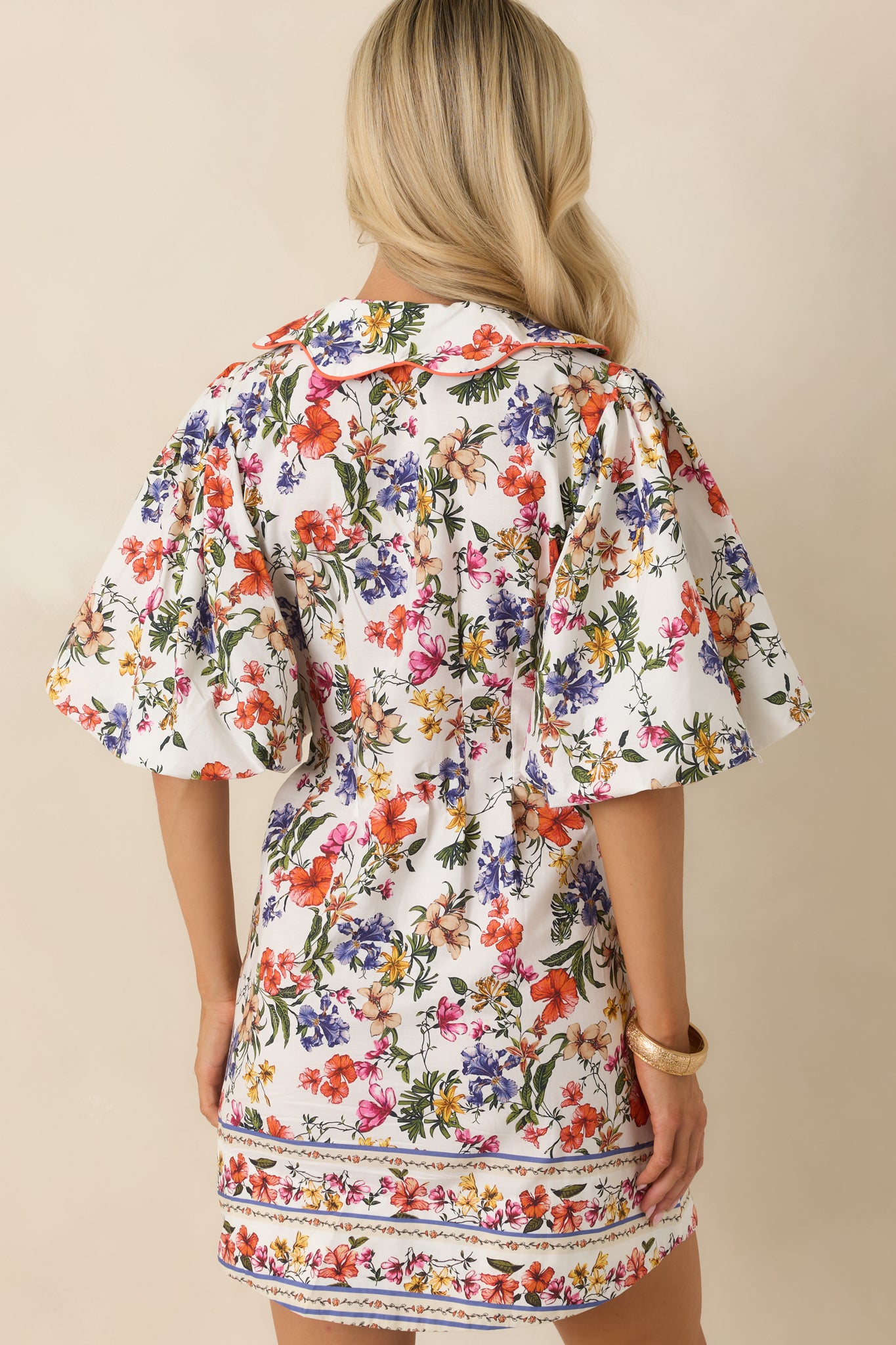 Ivory multi floral cotton dress shown from the rear, featuring a clean finish with continuous floral print and softly structured shaping through the back silhouette.