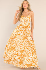 Full body view of this dress that features a sweetheart neckline, adjustable straps that tie at the back of the neck, ring detailing at the center of the bust and on the straps, a small cutout below the bust, a smocked section in the back, and a long, flowy skirt.