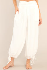 These white pants feature a high waisted design with cinching in the middle, a smocked insert in the back, functional hip pockets, a linen-like material, and self-tie drawstring cuffed ankles. 