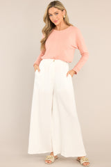 This pink top features a split bottom hem, a ribbed crew neckline, ribbed sleeve cuffs, and a soft peach colored fabric. 