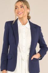 Front view of  this blazer that features a notch lapel collar, shoulder pads, a functional button, faux pockets, and faux buttons on the sleeves.