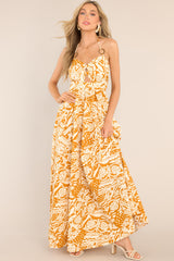This orange and cream dress features a sweetheart neckline, adjustable straps that tie at the back of the neck, ring detailing at the center of the bust and on the straps, a small cutout below the bust, a smocked section in the back, and a long, flowy skirt.