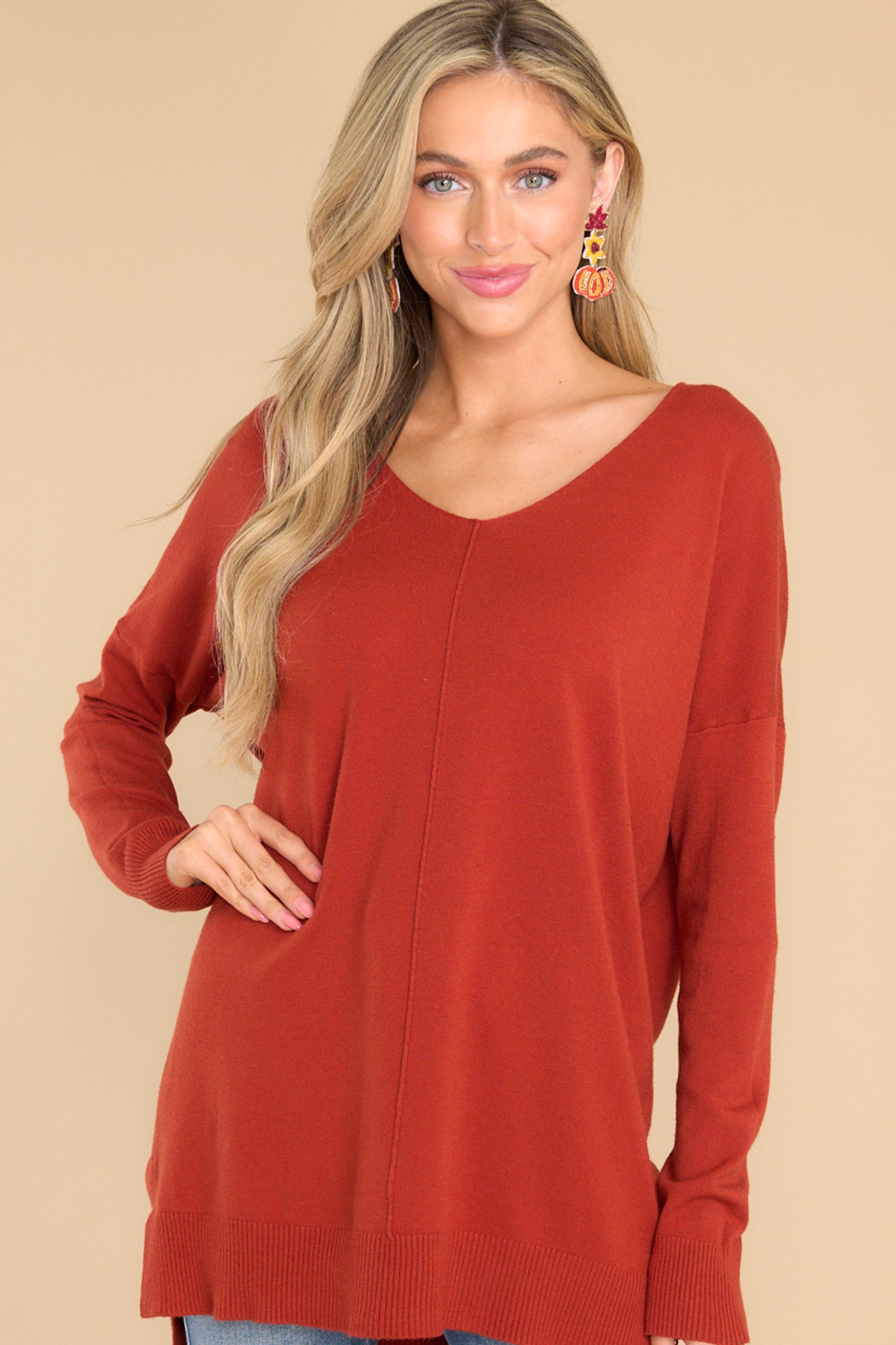Front view of sweater that features a v-neckline and a high-low hemline with slits at the sides.