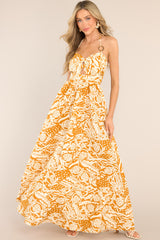 Front view of this dress that features a sweetheart neckline, adjustable straps that tie at the back of the neck, ring detailing at the center of the bust and on the straps, a small cutout below the bust, a smocked section in the back, and a long, flowy skirt.
