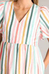 Close up view of this multi-colored dress features a v-neckline, puff sleeves, two functional pockets, and a slightly relaxed fit throughout.