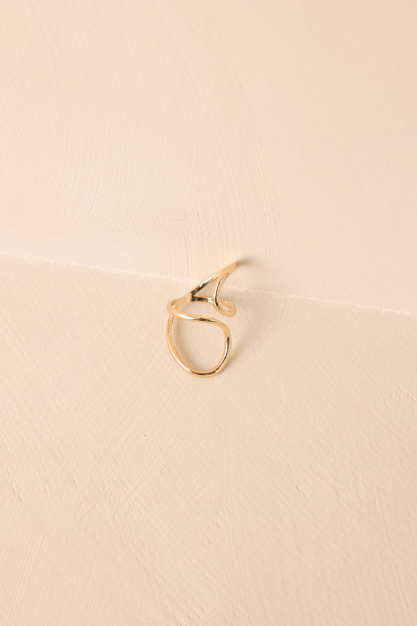 Cropped image focusing on the sculptural double-curve design and polished gold finish of the ring.
