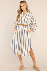 Front view of this dress that features a v-neckline, belt loops, an adjustable belt, functional pockets, elastic cuffed long sleeves, and a vertical striped pattern.