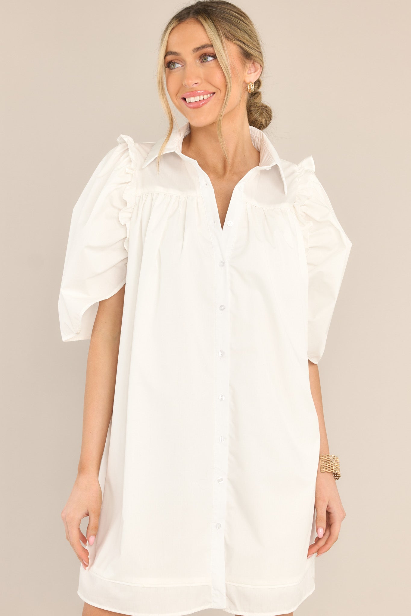Front view of this dress that features a collared neckline, functional buttons down the front, butterfly short sleeves, and ruffle detailing.