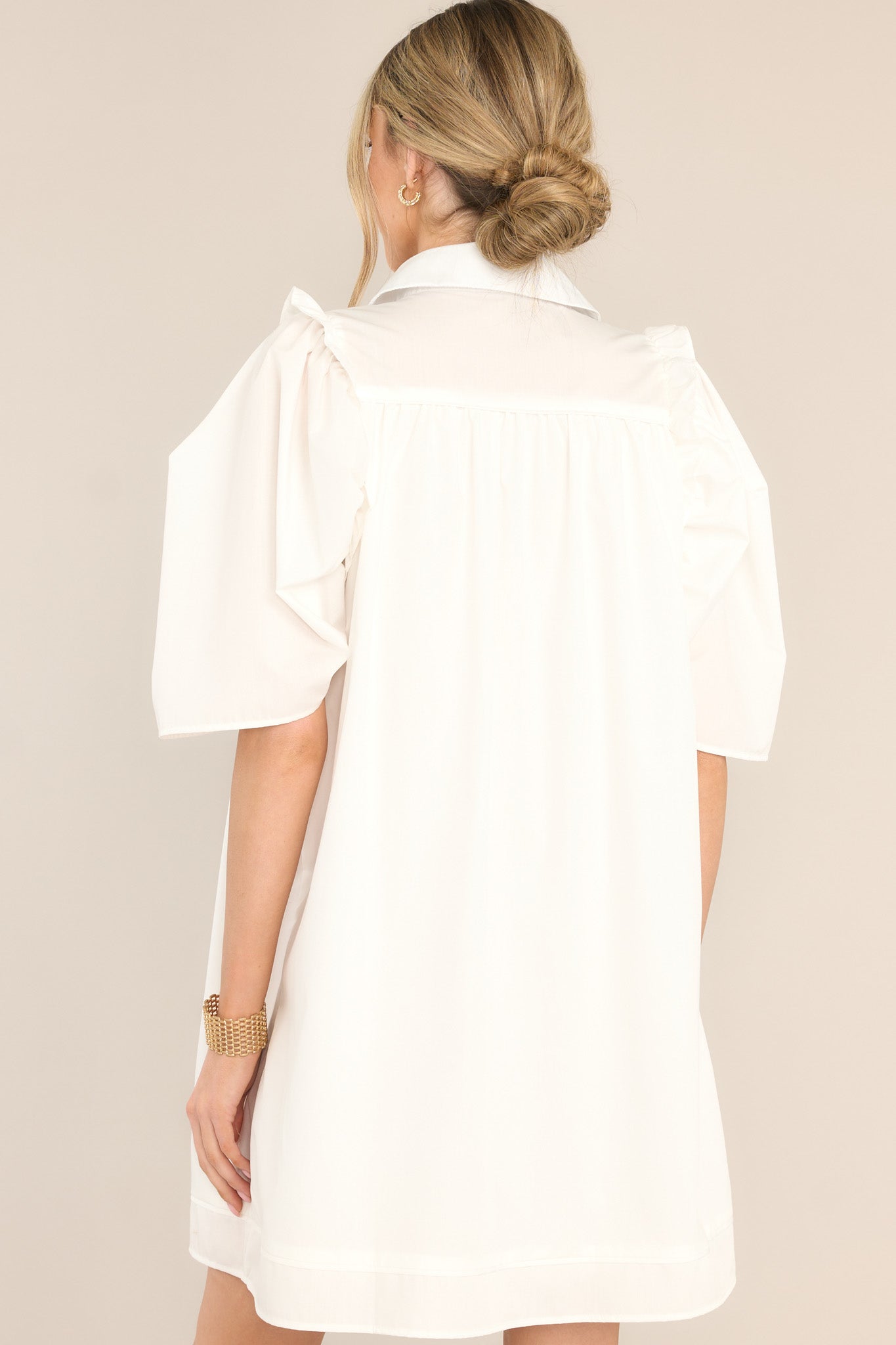 Back view of this dress that features a collared neckline, functional buttons down the front, butterfly short sleeves, and ruffle detailing.