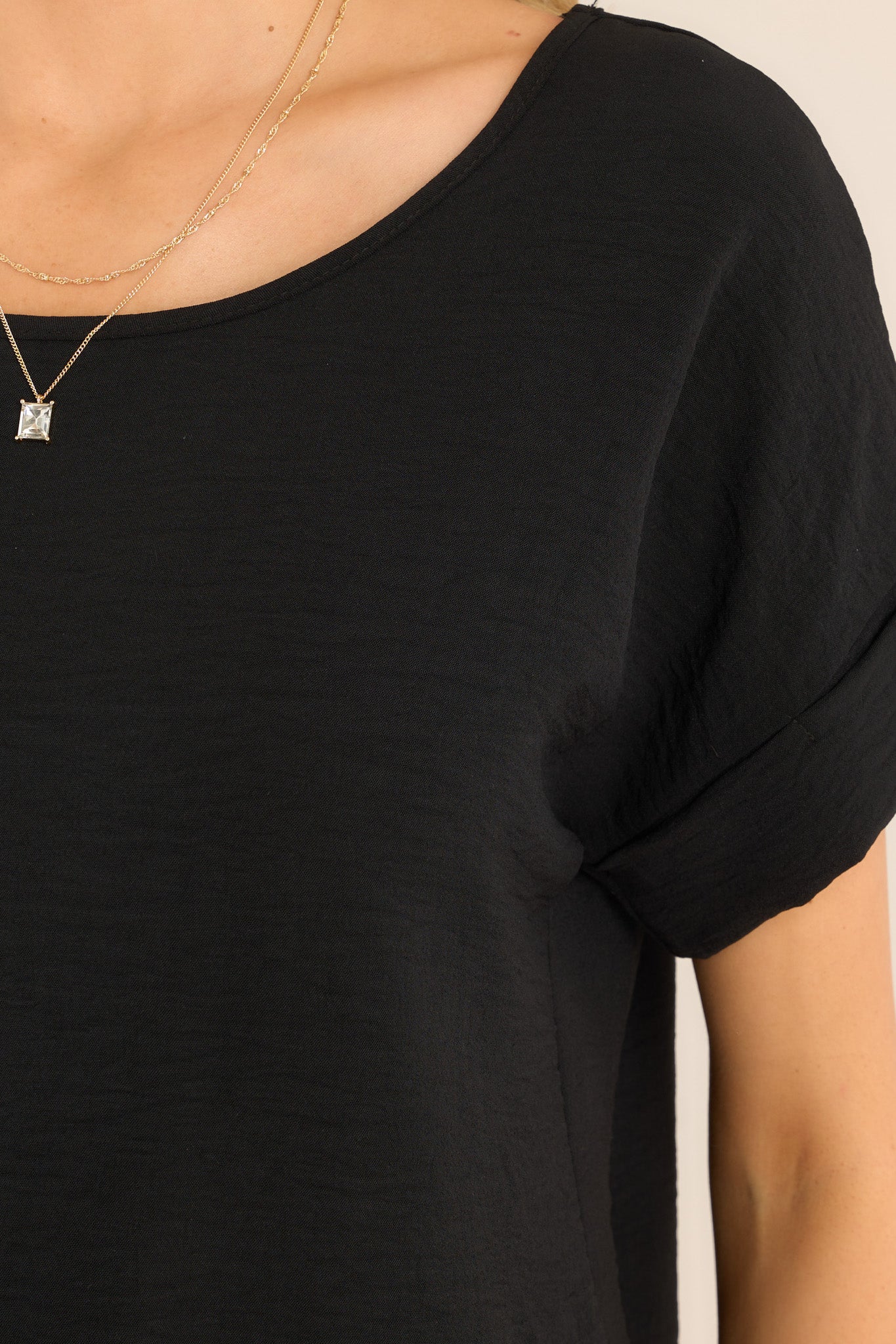 Close up view of this top that features a wide crew neckline, rolled & pinned short sleeves, and a relaxed fit. 