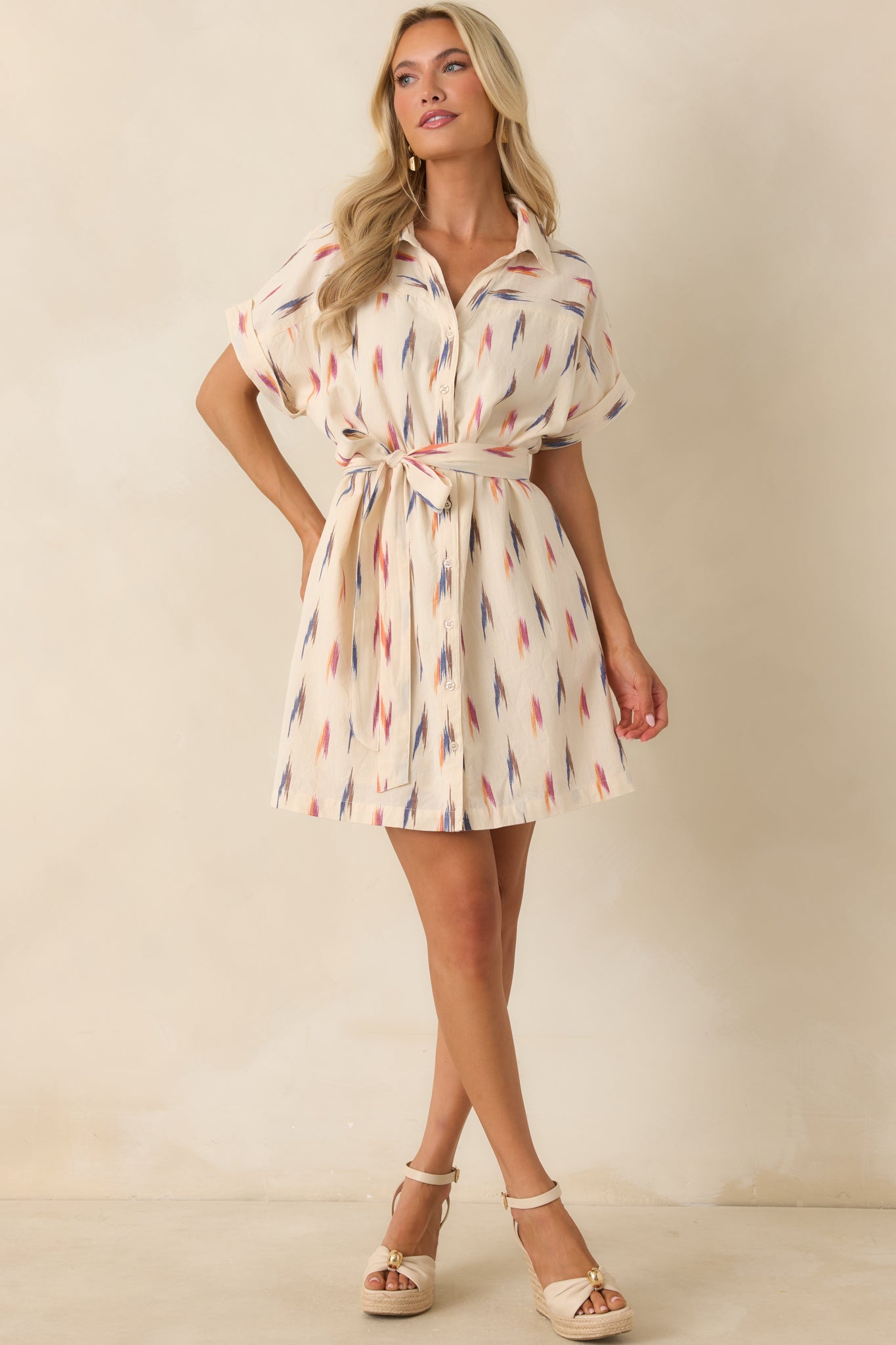 Cream cotton shirt dress showcasing a removable self-tie waist belt, collared structure, and allover painterly print design.