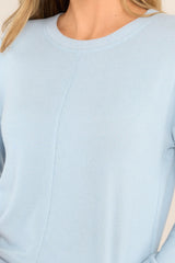 Close up view of this top that features a ribbed crew neckline, an exposed seam down the middle, ribbed cuffed long sleeves, and a ribbed split hemline.